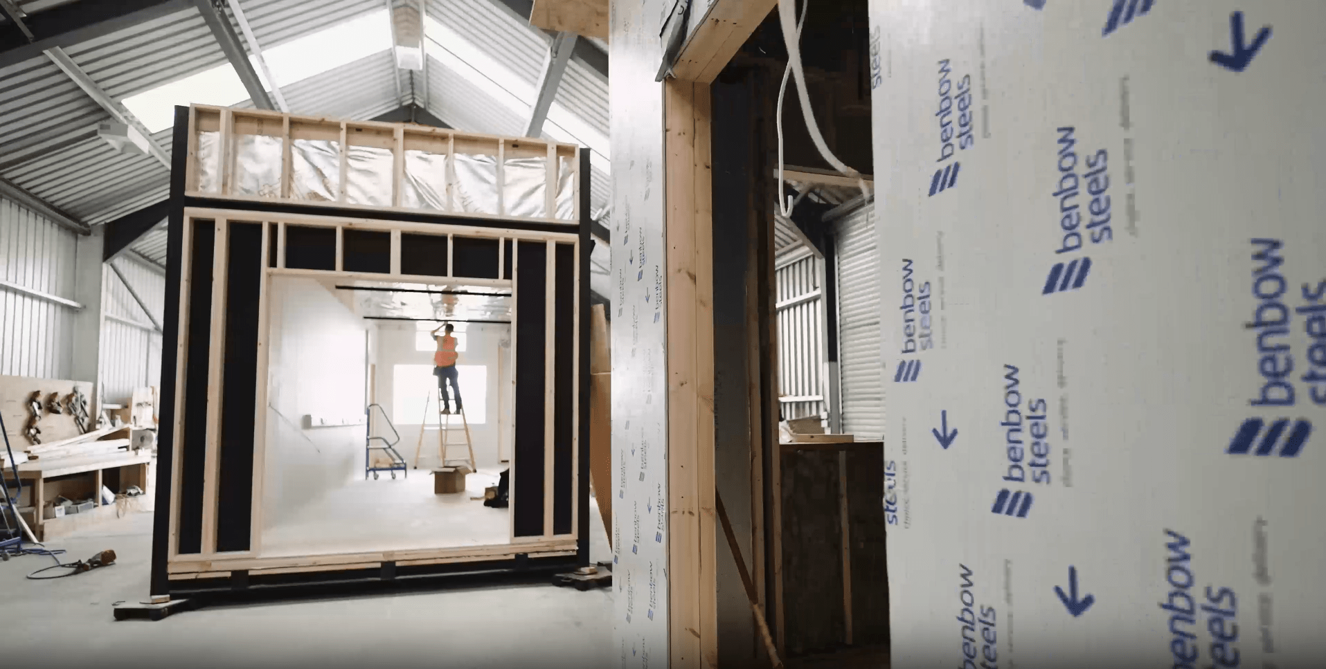 Image shows a worker manufacturing a modular building